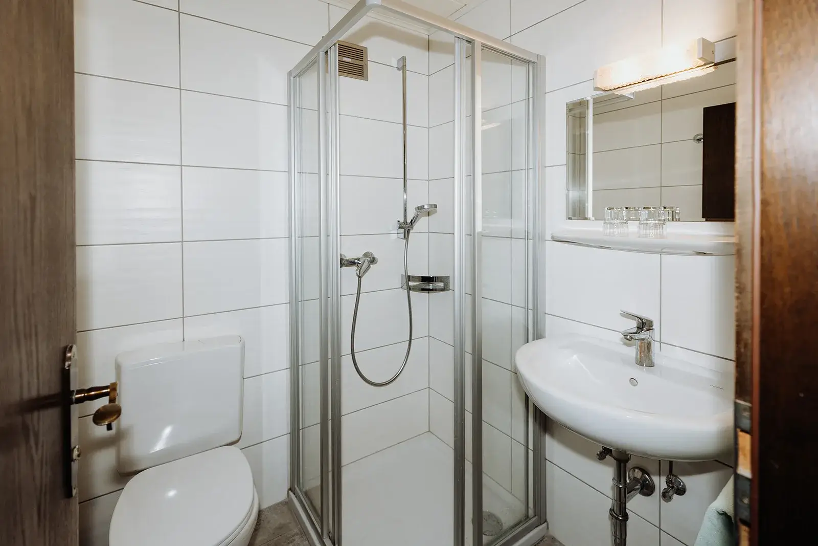 Kleines Badezimmer mit Dusche und weißen Fliesen.