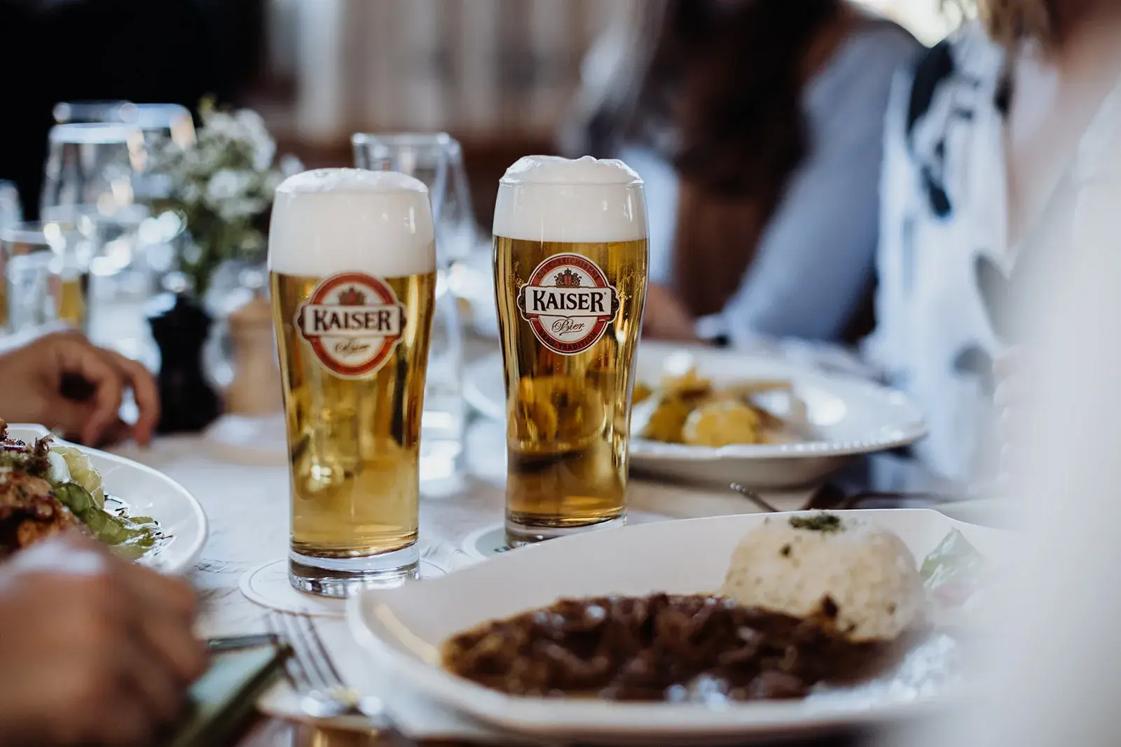 Zwei Gläser Kaiser Bier auf einem gedeckten Tisch.