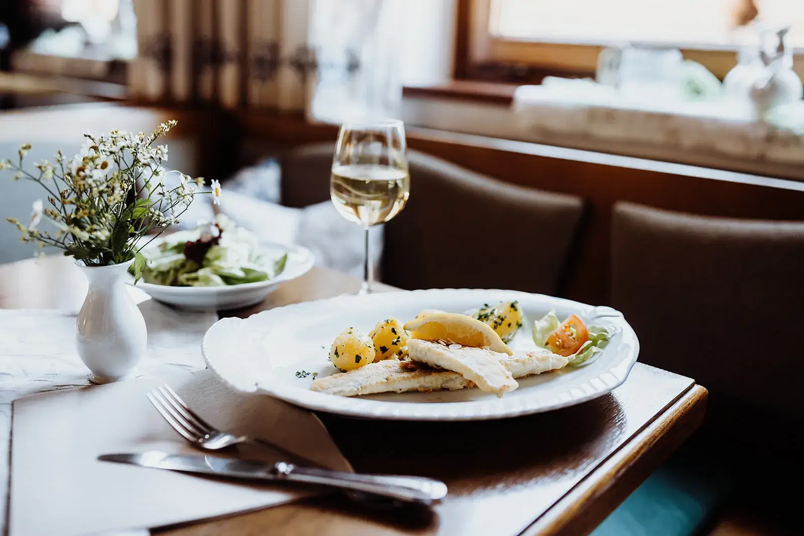 Gedeckter Tisch mit Speisen und Weißwein im Restaurant.