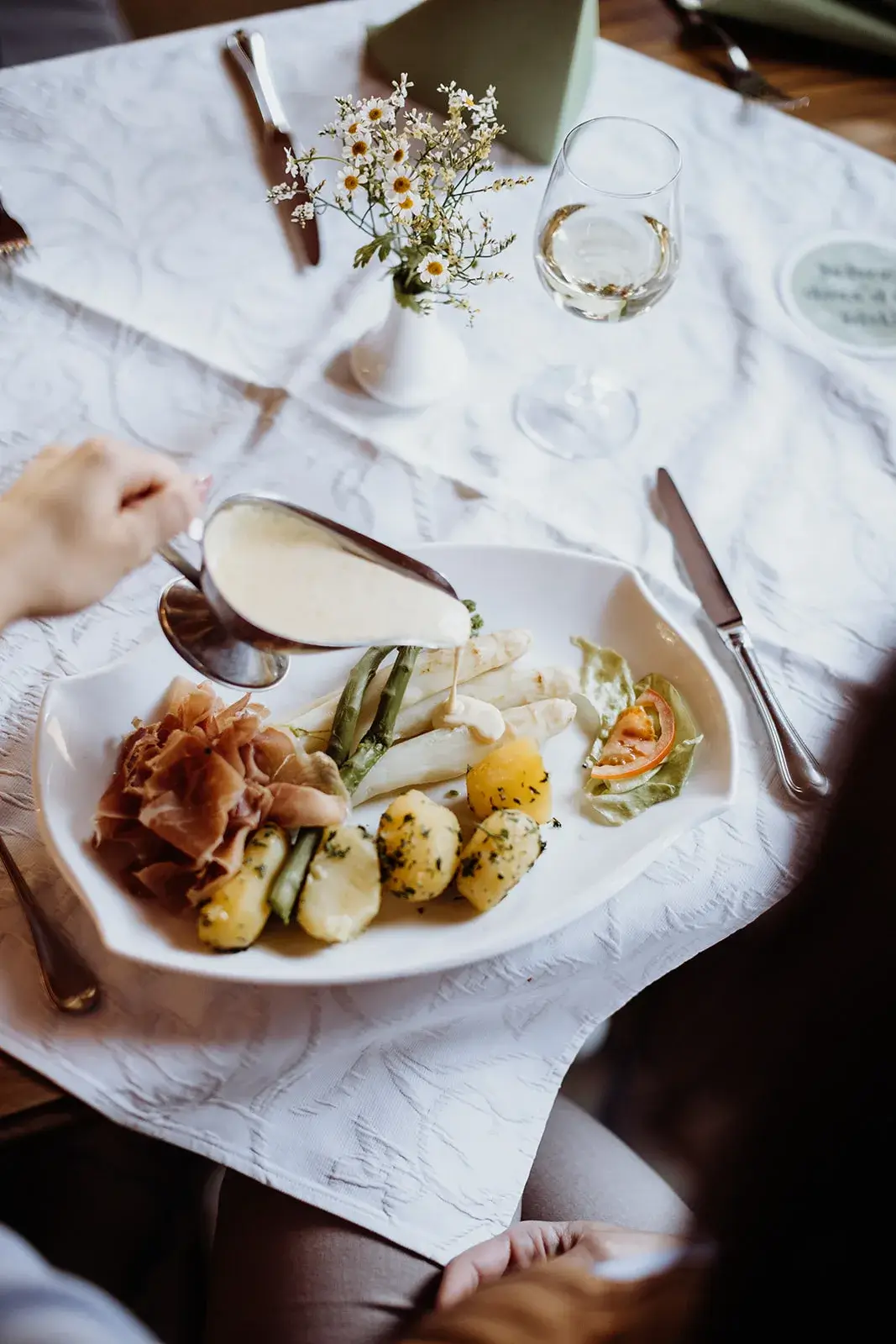 Spargelgericht mit Sauce und Gemüse auf elegantem Tisch.