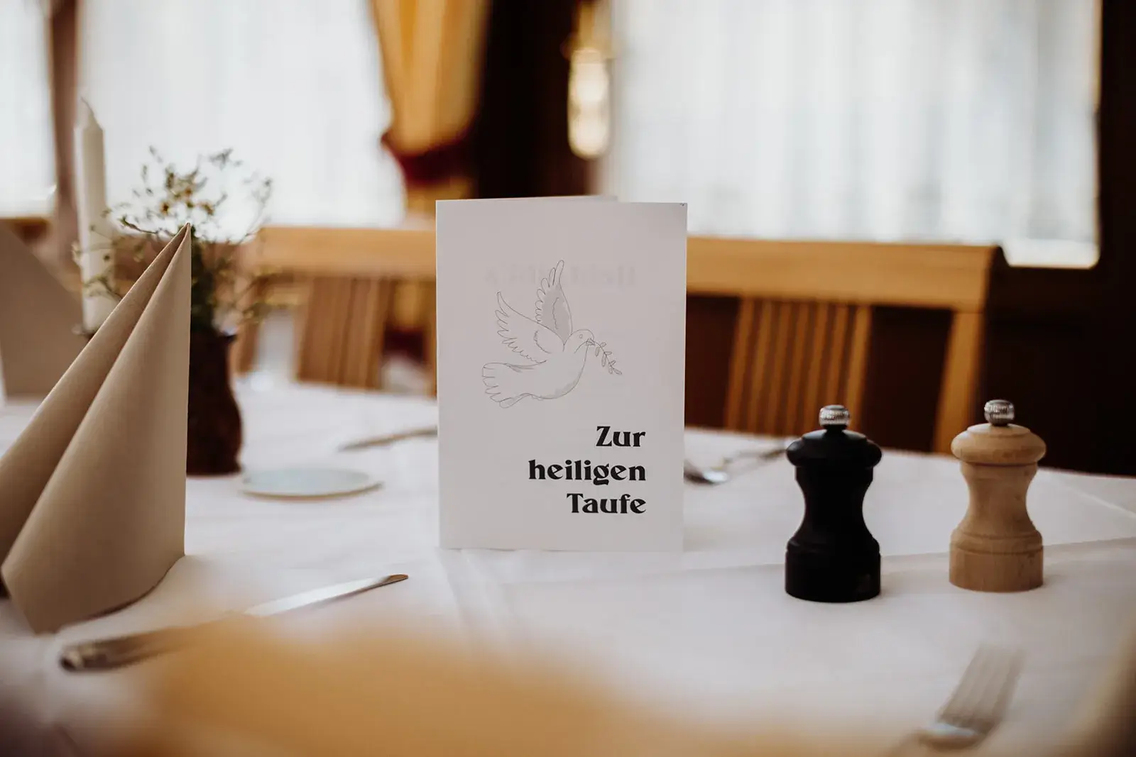Taufkarte auf gedecktem Tisch mit Pfefferstreuern.